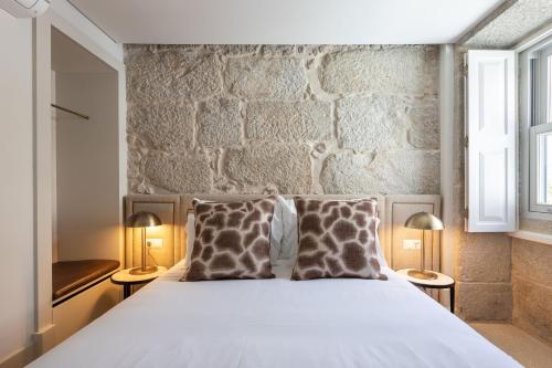a bedroom with a white bed with two pillows at Líbere Porto Laranjais in Porto