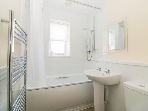 a white bathroom with a sink and a shower at Malting Cottage in Dawlish