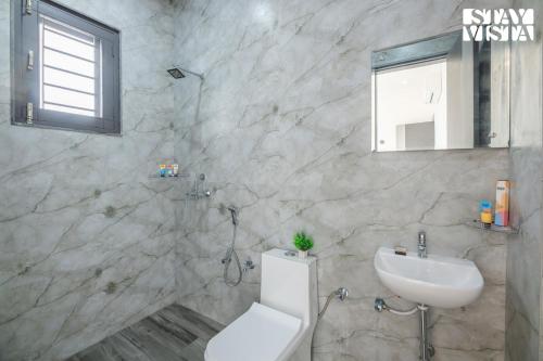a bathroom with a white toilet and a sink at StayVista at Pinkal Farms with Pool, Lawn, Wi-Fi in Jaipur