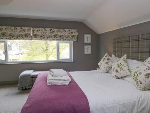a bedroom with a large white bed with a purple blanket at Osprey Cottage in Ambleside