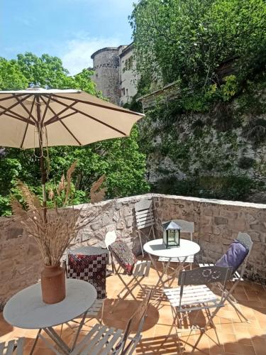 un patio avec tables, chaises et un parasol dans l'établissement Les volets bleus, à Vaison-la-Romaine