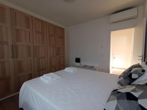 a bedroom with a white bed and wooden cabinets at Casa Bianca, Vista unica sul lago di Como in Dervio