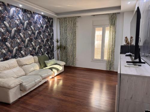 Una sala de estar con un sofá y un televisor. en Selva House Sevilla, en Coria del Río