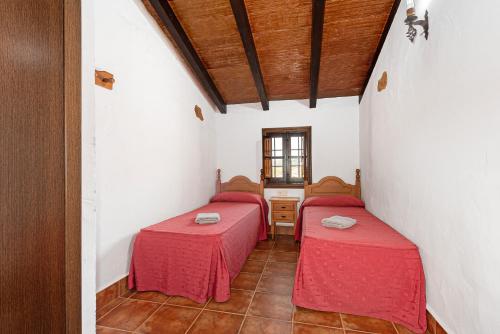 two beds in a room with red sheets at El Granero in Málaga