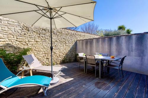 une table et des chaises avec un parasol sur une terrasse dans l'établissement Vauban 297 Studio, à Saint-Martin-de-Ré