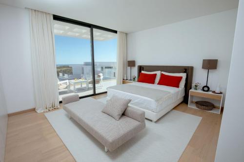 a bedroom with a bed with red pillows and a couch at Monte Rei 3 bed Penthouse Apt in Vila Nova De Cacela