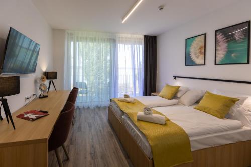 a bedroom with a large bed with a desk and a desk at NEKA Village in Balatonboglár