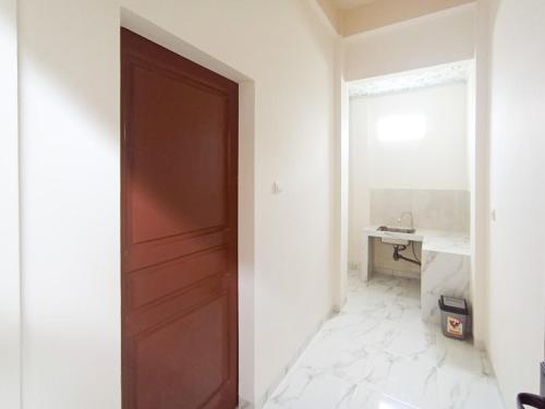 a brown door in a white room with a sink at Ghe Ai Homestay RedPartner in Tulungagung