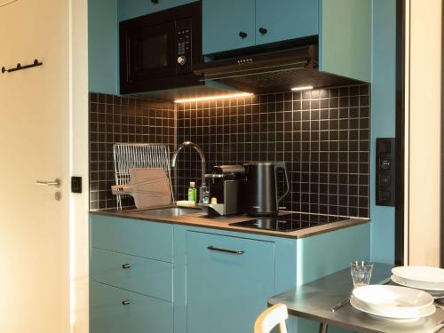 a blue kitchen with a sink and a microwave at Aparthotel Adagio Access Brussels Airport in Machelen