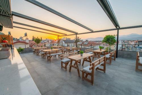 a restaurant with wooden tables and benches on a roof at Belci City House in Fethiye