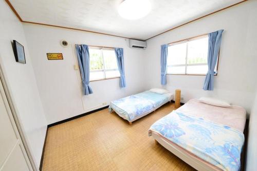 a bedroom with two beds and two windows at ペットＯＫ嘉手納基地に近い外人住宅Old America House -GuestHouseHead- in Kadena