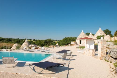 a resort with a swimming pool and lounge chairs at HelloAPULIA Trulli Flora - Charming Trulli with Private Pool and Garden in Noci