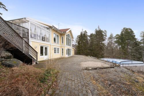 a large yellow house on top of a brick driveway at Fantastisk Villa med extra allt in Tyresö