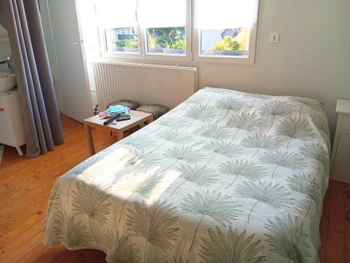 une chambre avec un lit, une table et des fenêtres dans l'établissement Chambre chez l'habitant, à Péronne