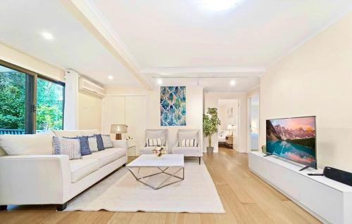un soggiorno con un divano bianco e una TV di Tranquil Retreat in Roseville With Garden Oasis a Sydney