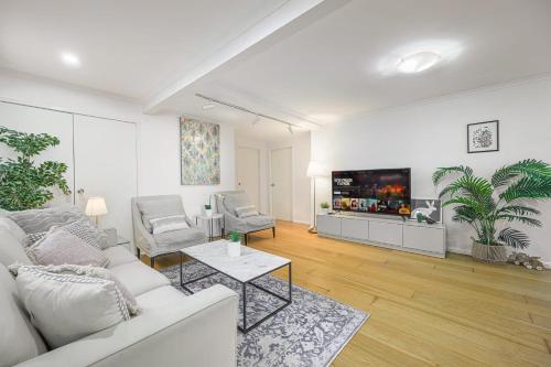 un soggiorno con un divano bianco e una TV di Tranquil Retreat in Roseville With Garden Oasis a Sydney