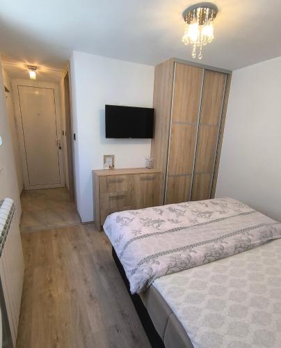 a bedroom with a bed and a tv on the wall at Apartman Vukalović in Trebinje
