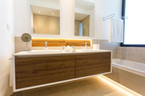 un bagno con un lavandino, uno specchio e una vasca di Monte Rei 1 bed apt a Vila Nova de Cacela