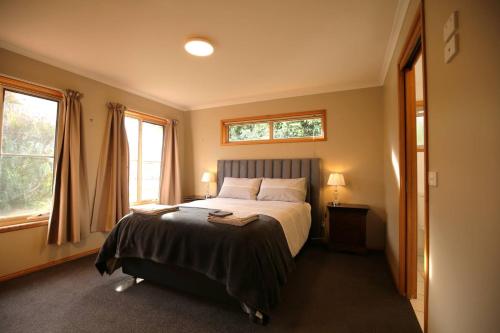 ein Schlafzimmer mit einem Bett und zwei Fenstern in der Unterkunft Bridgecroft Bungalow in Richmond