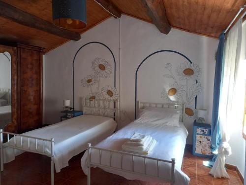 a bedroom with two beds with flowers on the wall at Artemilland B&B in Burzanella