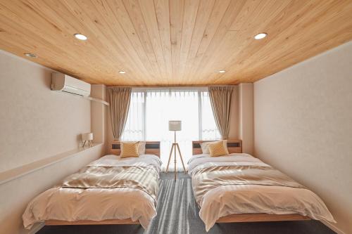 two beds in a room with a wooden ceiling at OHIO Motosan Shukuba in Takasaki