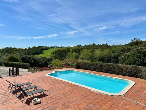 a swimming pool on a brick patio with two lounge chairs at Quinta da Fonte - Casa da Charrete in Caldas da Rainha