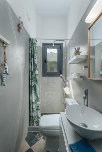 a white bathroom with a sink and a toilet at La Pausa in Porto Heli