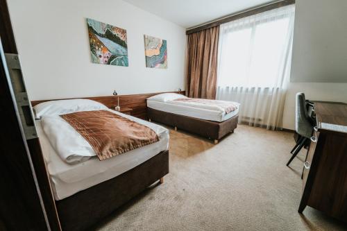 a hotel room with two beds and a window at Penzion Drak in Liptovský Mikuláš