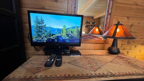 a computer monitor on a table with a lamp and remote controls at Smokey Joes cabin in Zephyr Cove