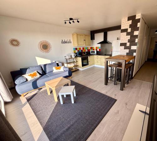 un salon avec un canapé bleu et une cuisine dans l'établissement Le Panoramic vue mer, à Calais
