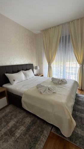 a bedroom with a large white bed with curtains at Apartman Sunce Lux A in Vrnjačka Banja