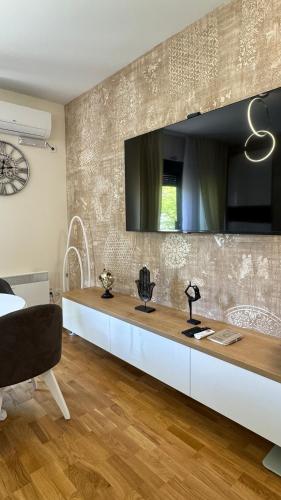 a living room with a long table with a tv on the wall at Apartman Sunce Lux A in Vrnjačka Banja