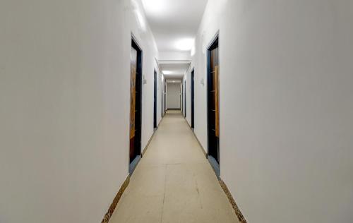 un pasillo con paredes blancas y un pasillo largo en Hotel O HR, en Kundakal
