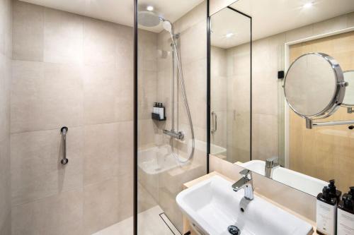 a bathroom with a shower and a sink and a mirror at Mercure Katowice Centrum in Katowice