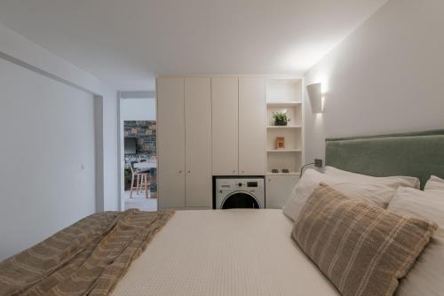 a white bedroom with a bed and a kitchen at Seannamon Apartment with sea view by 8essentially in Agios Nikolaos