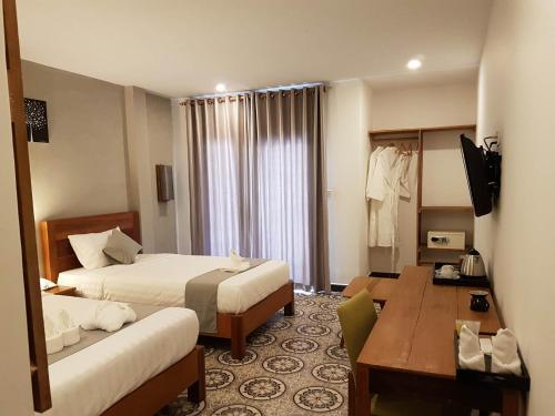 a hotel room with two beds and a desk at Home Chic Hotel in Phnom Penh