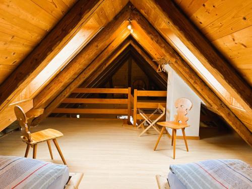 a attic room with a bed and two chairs at Ferienwohnung Haus Itten gemütlich und rustikal in Hondrich