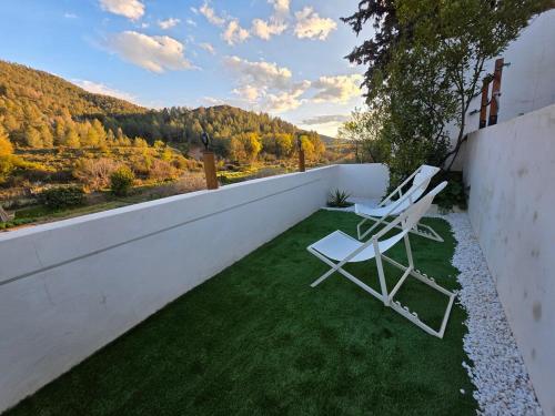 two white chairs sitting on the side of a wall at Domo AWA Magia y Naturaleza in Ucenda