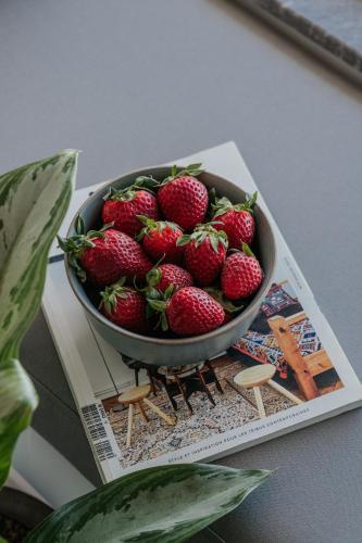 a bowl of strawberries sitting on top of a magazine at Seannamon Apartment with sea view by 8essentially in Agios Nikolaos