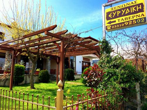 a wooden pergola in front of a building with a sign at Evridiki in Vergina