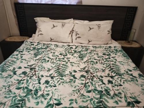 a bed with a green and white comforter with birds on it at Phindulo Bed and Breakfast - No Loadshedding, Smart TVs & unlimited free fibre wifi in Krugersdorp