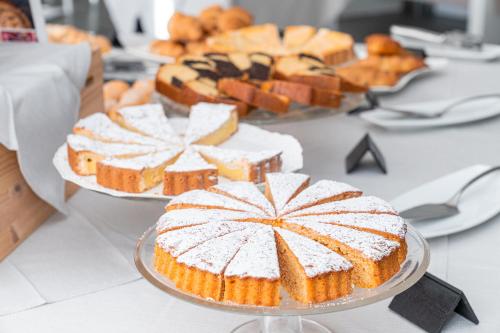 a table topped with cakes and other desserts on plates at Mercure Olbia in Olbia