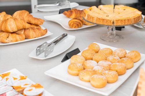 a table topped with plates of pastries and bread at Mercure Olbia in Olbia