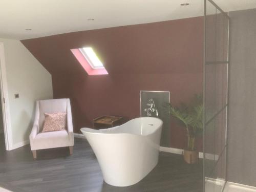 a bathroom with a bath tub and a chair at Elrick Estate - Elrick House in Newmachar
