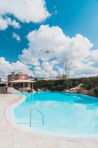 an airplane flying over a swimming pool with a helicopter at Mercure Olbia in Olbia