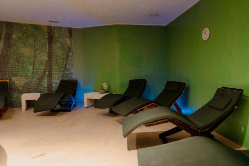 a room with green walls with chairs and a clock at Mercure Olbia in Olbia