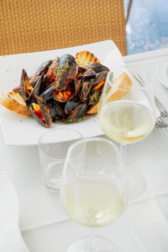 a plate of mussels and a glass of wine on a table at Mercure Olbia in Olbia