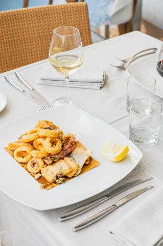 a plate of food on a table with a glass of wine at Mercure Olbia in Olbia