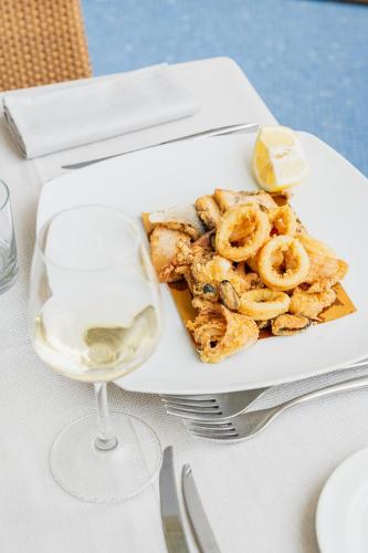 a plate of food with shrimp and a glass of wine at Mercure Olbia in Olbia