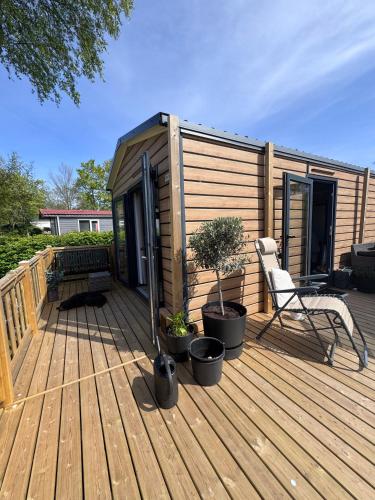 a tiny house with a chair on a deck at Chalet Pampusplaat 16 in Lauwersoog